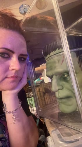 Reviewer showing the detailed Frankenstein Monster Crossbody Bag inside its clear packaging.