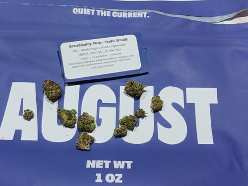 Reviewer's Granddaddy Purp Exotic Smalls buds displayed on top of the large purple packaging.