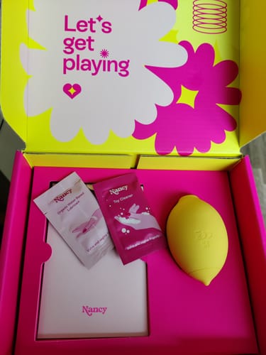 Customer shows the inside of a colorful box containing a yellow object and two packets.