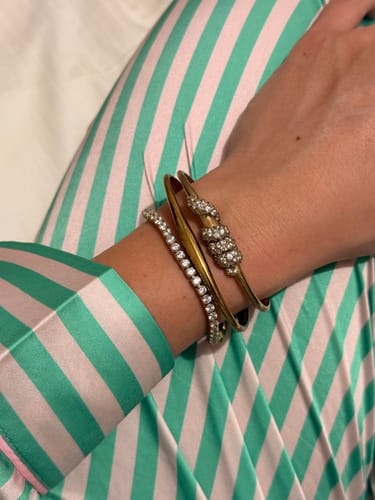 Customer wearing the Luxe Tennis Bracelet stacked with two other bracelets on their wrist, against a striped sleeve.