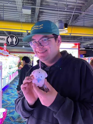 Reviewer smiling in an arcade while wearing the green Big Lightweight Nylon Hat.
