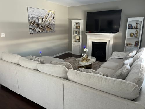 Customer's 'Peaceful Glow' Framed Canvas hanging on a living room wall above a large, light-colored sofa.