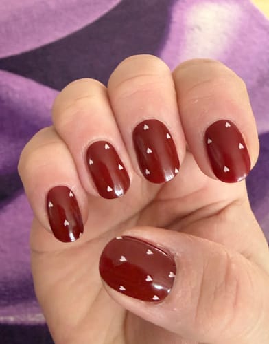 Hand einer Kundin mit den UV-Gel-Folien 'Dainty Little Love' auf kurzen, gepflegten Nägeln.