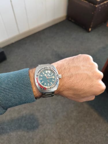 Cliente mostrando su reloj Vostok Amphibia en la muñeca, destacando su esfera verde.