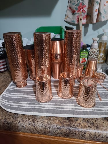 Customer's multiple hammered Pure Copper Carafe & Tumbler Sets washed and drying on a striped towel.