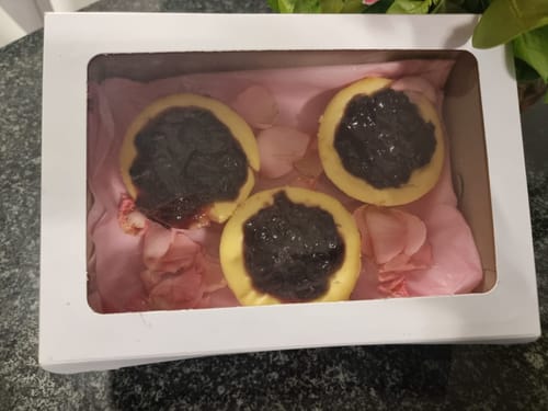 Customer's three individual Blueberry Cheesecakes displayed in a white gift box with pink petals.