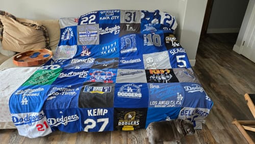 Customer's large Premium T-Shirt Quilt made from LA Dodgers shirts, draped over a couch.