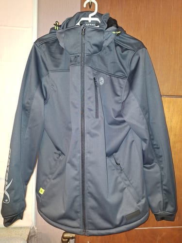 Recensent toont de donkergrijze Wind Blocker Jacket met capuchon aan een kledinghanger.