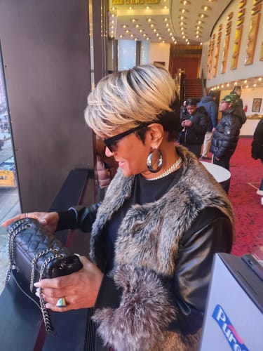 Reviewer looking stylish wearing the Zury Sis Sassy wig, a short, shaggy cut with blonde hair and dark roots.