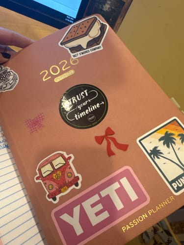 Reviewer holding their pink Passion Planner, personalized with many stickers.