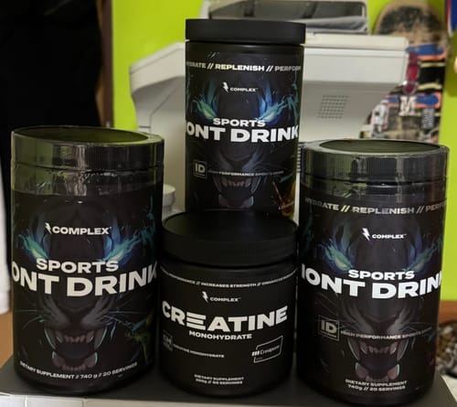 Reviewer's three black tubs of Sports Iont Drink and a tub of Creatine arranged on a surface.