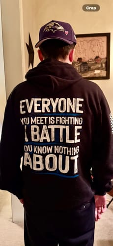 Reviewer from behind wearing the black Be Kind hoodie, showing the large text design on the back.