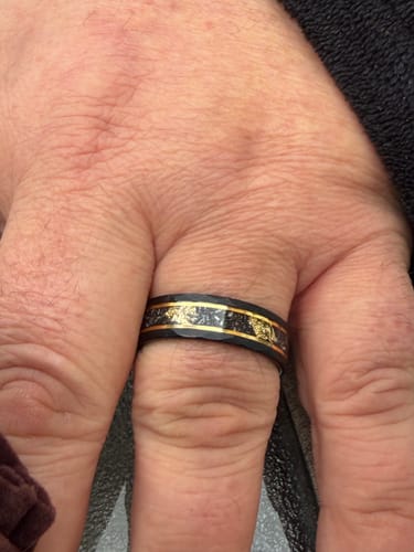 Close-up of a customer wearing the black Aureum ring with its gold foil inlay on their finger.