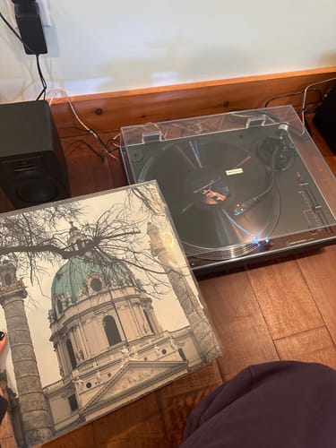Customer's custom vinyl record on a turntable, with the personalized album sleeve featuring a building shown next to it.