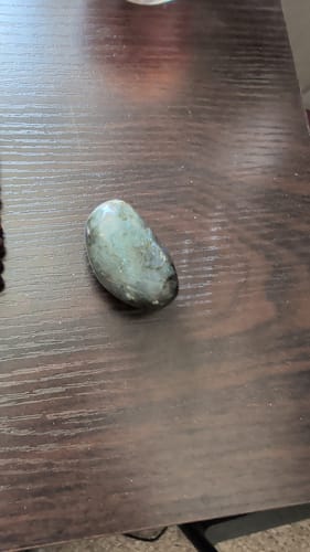 Customer's polished labradorite crystal from the VIP Crystal Club, resting on a dark wood table.