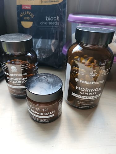 Reviewer's Bee Repair Balm jar on a counter next to other wellness products.