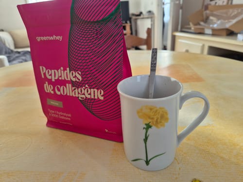 Client montrant son sachet rose de Peptides de Collagène à côté d'une tasse.