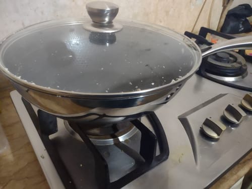 Customer's Honeycomb Laser Crafted 12-Inch Pan with its glass lid on, sitting on a gas stove.