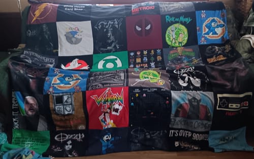 A customer's large Premium T-Shirt Quilt spread over a couch, made from many graphic pop-culture t-shirts.
