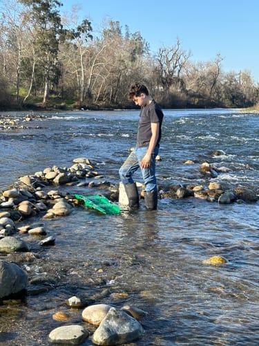 Reviewer standing in a rocky river with the green 6X22 Expedition Sluice Box in the water.