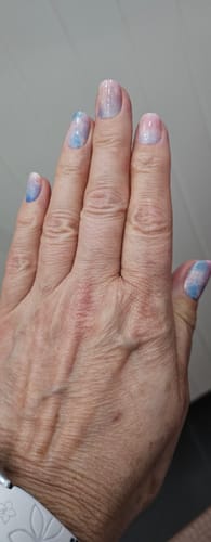 Eine Kundin zeigt ihre Maniküre mit den dezenten Rainbow Vision UV Gel Wraps in einem Pastell-Farbverlauf.