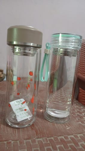 Reviewer's two Double Decker glass bottles on a tiled surface, one with a tan lid and one with a clear and green lid.