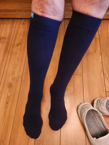 Customer wearing the dark knee-high Performance Eucalyptus Compression Socks on a wood floor.