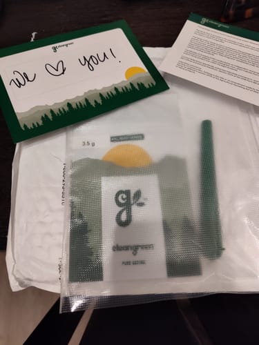 Customer's Roll Ready Ground flower in its clear packaging, shown with a handwritten thank you note and a green cone.