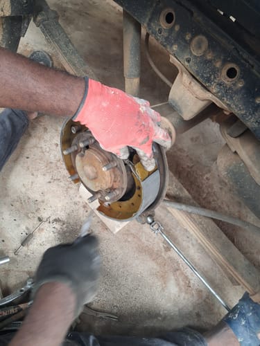 Customer installing the new Brake Shoes for a Nissan Np300 onto a car's wheel drum.