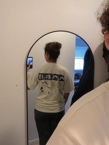 Reviewer in a mirror selfie showing the fit and graphic on the back of their Sake Night T-Shirt.