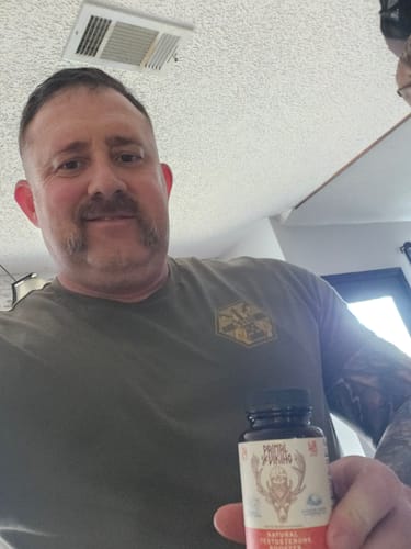 Reviewer smiling while holding a bottle of Primal Reindeer Testosterone Support.