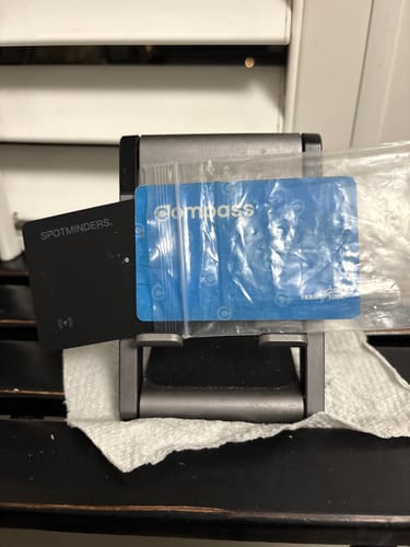 Customer's black SPOTMINDERS Tracking Card displayed next to a blue Compass card on a small stand.