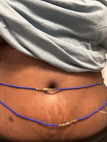 Close-up of a reviewer wearing two blue and gold Lux Elastic Clasp Waist Beads around their waist.