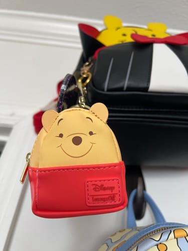 Customer's cute Winnie the Pooh mini backpack keychain clipped onto the strap of another backpack.