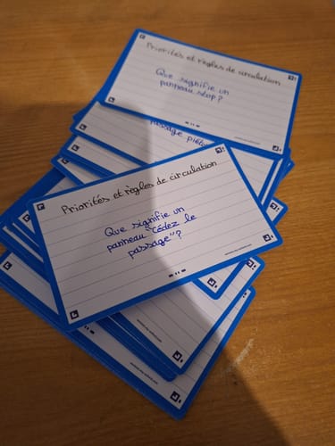 Client montrant ses fiches de révision FLASH 2.0 manuscrites pour étudier les règles de circulation.