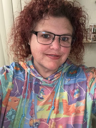 Reviewer in a selfie wearing the colorful Disney 'A Goofy Movie' Performance Hoodie, showing its pastel print.