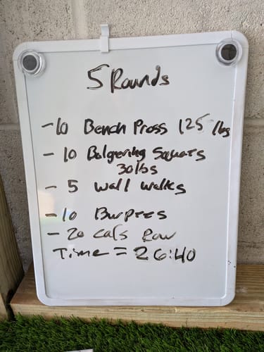 Reviewer's whiteboard showing a written workout routine, providing context for their use of SuperCharged Honey.