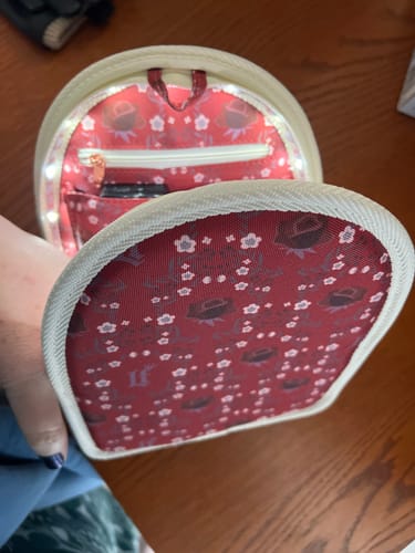 Reviewer's Loungefly bag organizer insert shown open with its interior light on, illuminating the red floral lining.