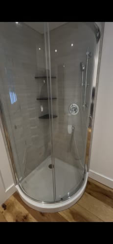 Customer's metal shower slide bar and handheld head installed in an elegant, tiled corner shower.