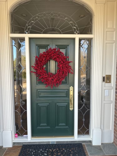 Customer's full, red Thimble Berry Wreath hanging on a green front door.