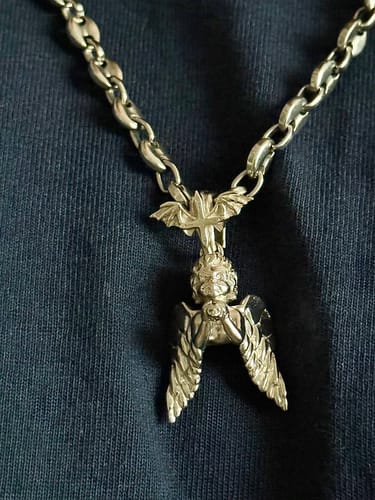 Customer wearing the 6MM MINI INFINITY CHAIN with a detailed angel pendant against a dark shirt.