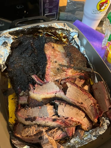 Reseñador muestra un Pecho Pieza Básica cocido y rebanado con una costra oscura en una bandeja.