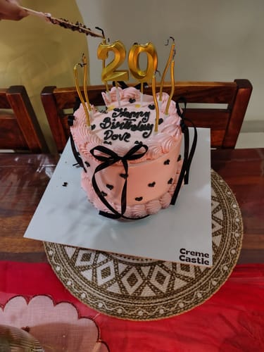 Customer's Pink Vintage Anniversary Cake decorated with a black ribbon, hearts, and gold candles for a 29th birthday celebration.