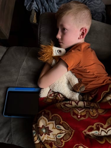 Customer's child cuddling the soft Tali Plushie while resting on a couch.