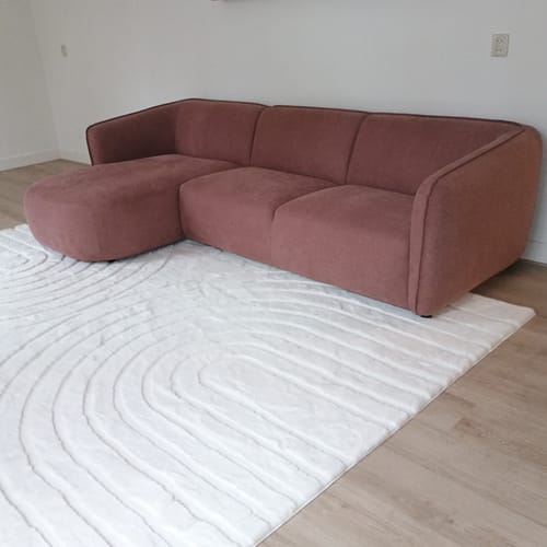 Recensent toont de oud roze by fonQ Soft hoekbank met chaise longue in een woonkamer op een wit kleed.