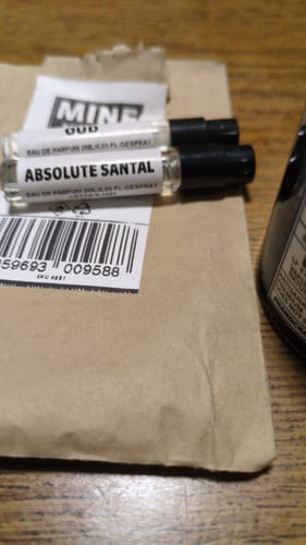 Cliente mostra i due campioni omaggio, uno con l'etichetta 'Absolute Santal' visibile.