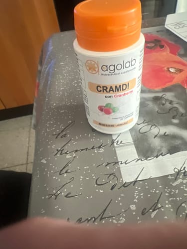 Recensore mostra un flacone bianco di Cramdi con tappo arancione, appoggiato su un tavolo.