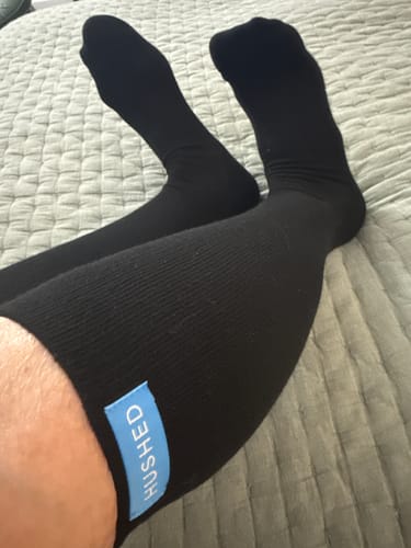 Reviewer shows the snug fit of the black Performance Eucalyptus Compression Socks on their legs while resting.