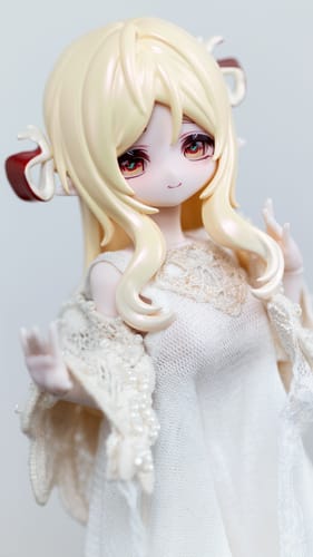 Close-up of a customer's Minty Little Lucky Spirits AnYao figure, highlighting its detailed face and blonde hair in a white dress.
