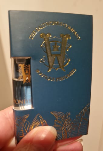 Customer holding a Honeyberry fragrance sample vial in its decorative blue card.